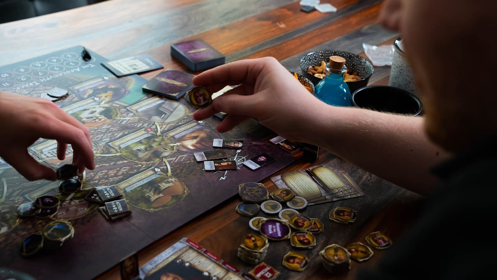 Two players sitting at a table playing a tabletop word and card game